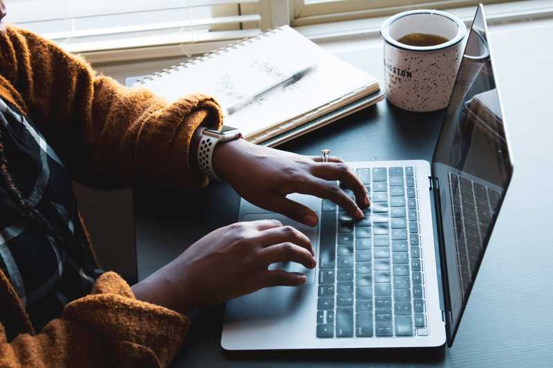 A view of a woman's hands as she is typing at her laptop. 