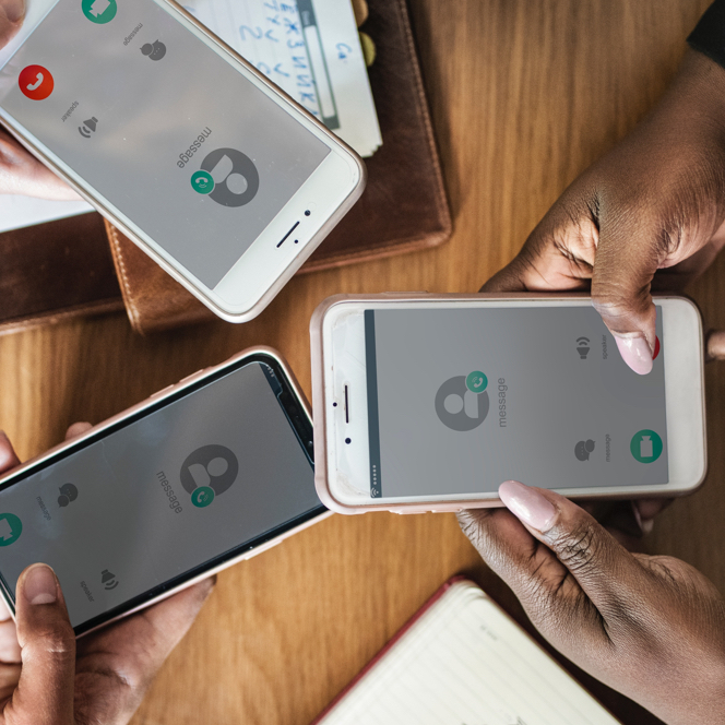 A zoomed in view from above of three people holding smartphones.